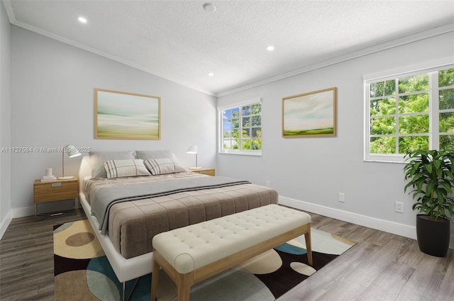 bedroom featuring multiple windows, a textured ceiling, ornamental molding, and hardwood / wood-style floors