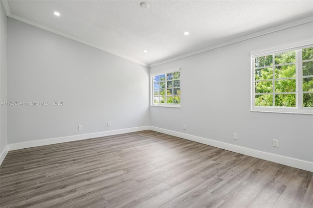 unfurnished room with wood-type flooring, a wealth of natural light, crown molding, and a textured ceiling