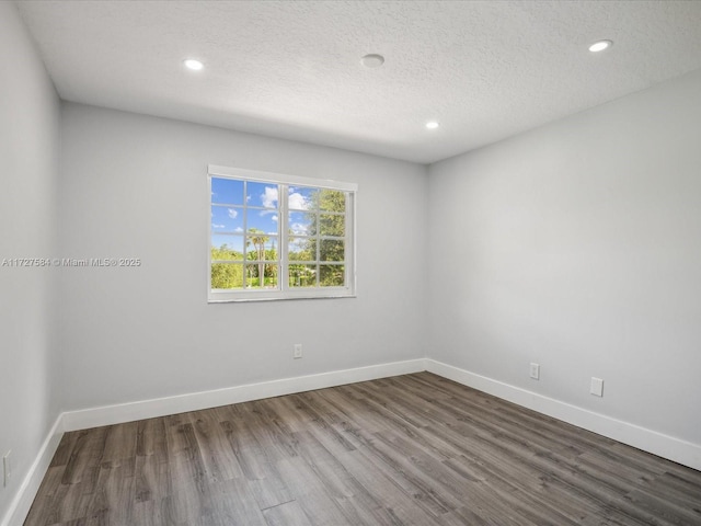 empty room with a textured ceiling and hardwood / wood-style flooring