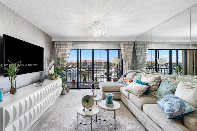 living room with wood-type flooring, a notable chandelier, a wealth of natural light, and a textured ceiling