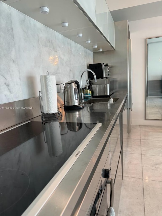 kitchen with sink, white cabinetry, tile walls, and light tile patterned flooring