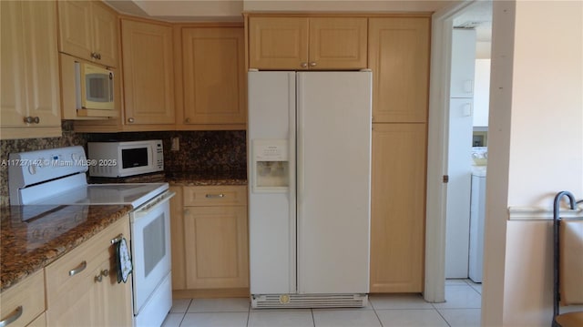 kitchen with light tile patterned floors, decorative backsplash, dark stone countertops, and white appliances