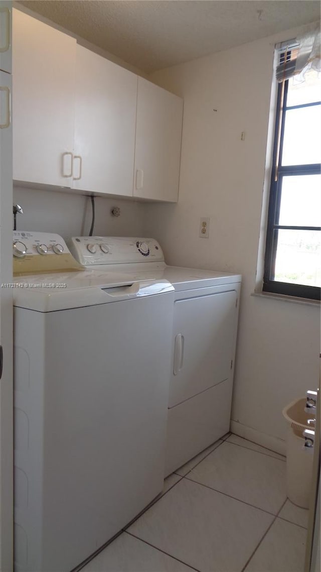 laundry area with cabinets, separate washer and dryer, and light tile patterned flooring