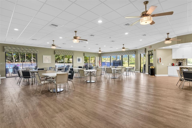 dining area with a paneled ceiling, plenty of natural light, and wood-type flooring