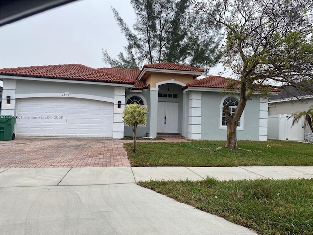 mediterranean / spanish-style home featuring a garage and a front lawn