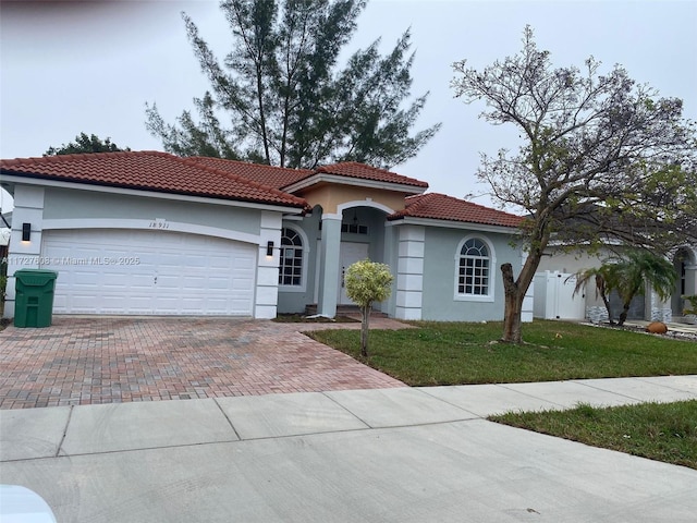 mediterranean / spanish-style house featuring a garage and a front lawn