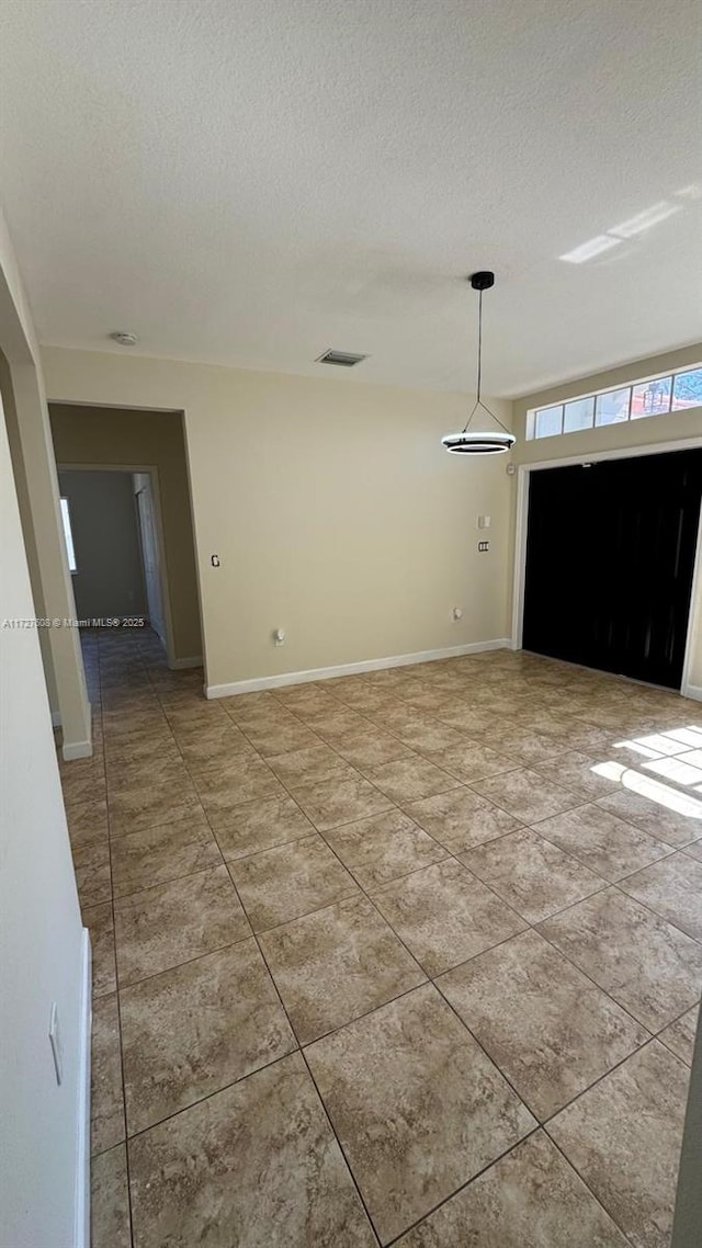 tiled empty room featuring a textured ceiling