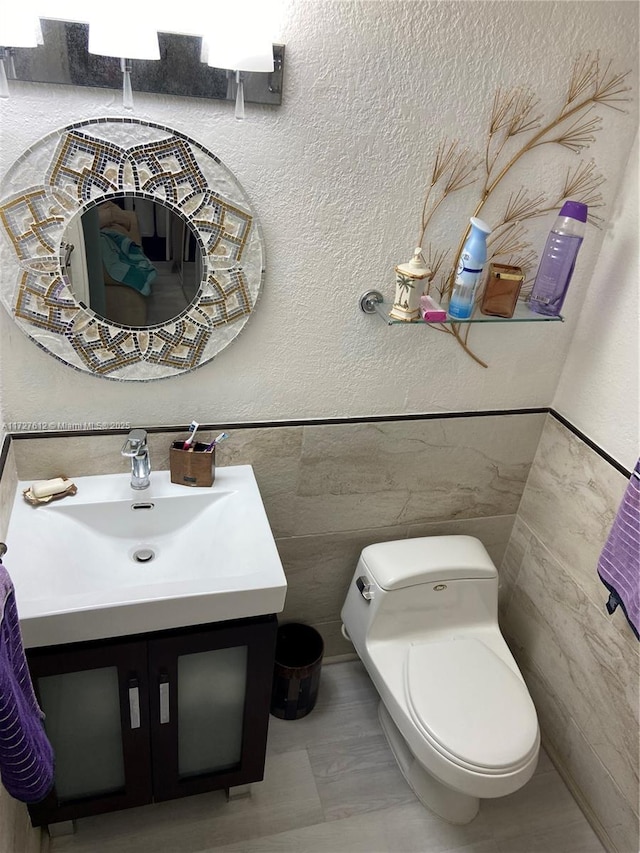 bathroom featuring vanity, tile walls, and toilet