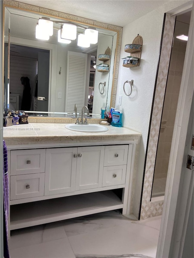 bathroom featuring tiled shower and vanity