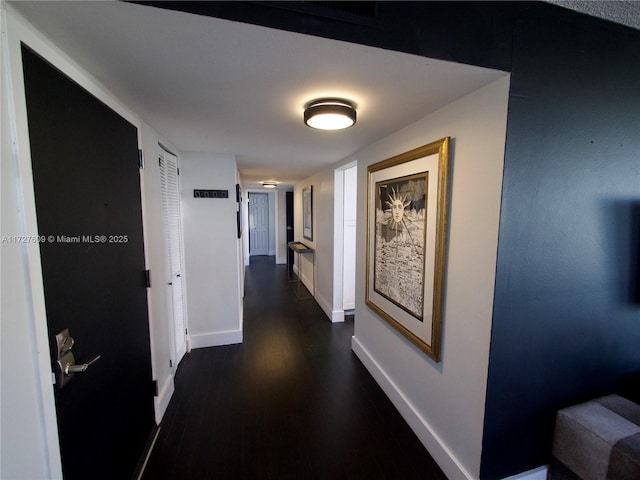 hallway with dark wood-style flooring and baseboards