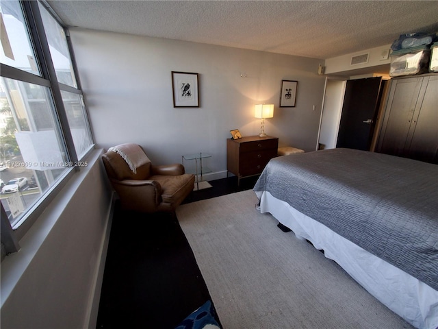 bedroom featuring visible vents, a textured ceiling, and baseboards