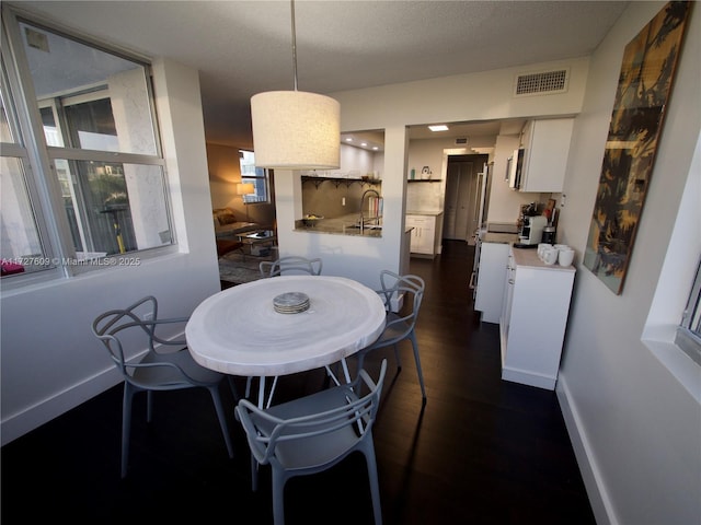 dining area featuring baseboards, visible vents, and dark wood-style flooring