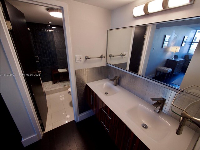 bathroom featuring a tile shower, vanity, hardwood / wood-style flooring, and toilet