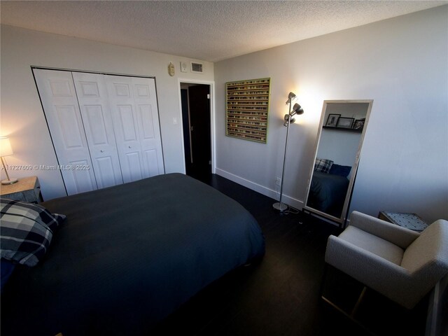 bedroom with dark wood-type flooring, a closet, and a textured ceiling