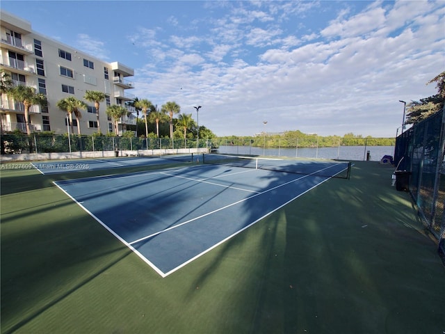 view of sport court featuring a water view and fence