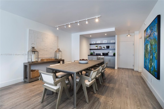 dining room featuring wine cooler, built in shelves, and hardwood / wood-style flooring