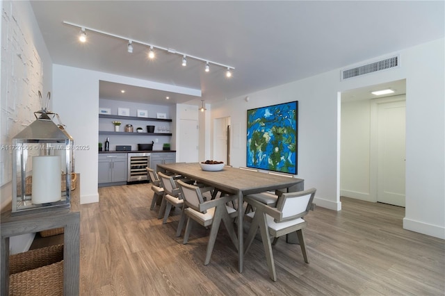 dining space featuring light wood-type flooring and beverage cooler