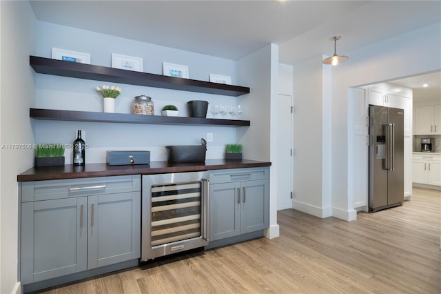 bar with wood counters, gray cabinetry, wine cooler, light hardwood / wood-style flooring, and high end refrigerator