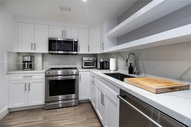 kitchen featuring white cabinets, decorative backsplash, sink, and stainless steel appliances