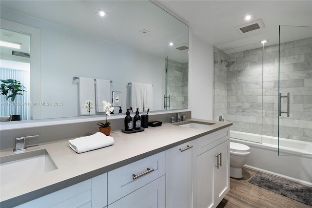 full bathroom featuring wood-type flooring, combined bath / shower with glass door, vanity, and toilet