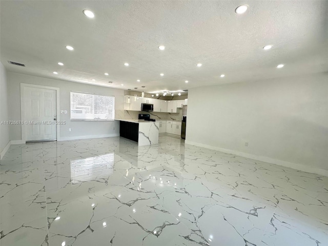 kitchen with white cabinets, a kitchen island, stainless steel appliances, and a textured ceiling