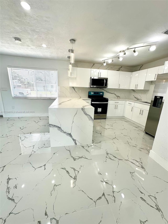 kitchen with white cabinets, light stone countertops, stainless steel appliances, and pendant lighting