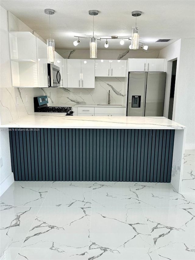 kitchen with appliances with stainless steel finishes, decorative backsplash, white cabinetry, and hanging light fixtures