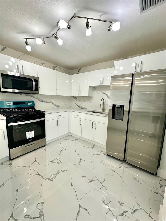 kitchen with tasteful backsplash, sink, white cabinetry, a textured ceiling, and stainless steel appliances