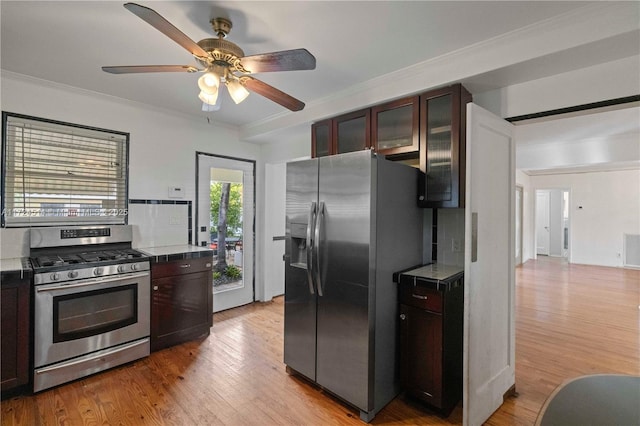 kitchen with light hardwood / wood-style flooring, ceiling fan, appliances with stainless steel finishes, dark brown cabinets, and ornamental molding