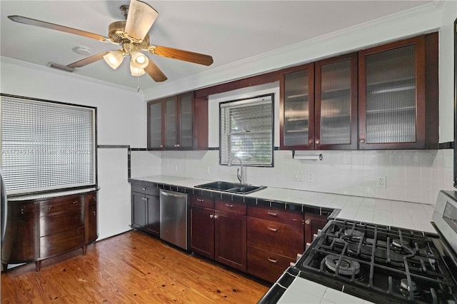 kitchen with sink, crown molding, appliances with stainless steel finishes, tasteful backsplash, and tile countertops