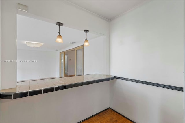 interior space with hardwood / wood-style floors, crown molding, and tile countertops