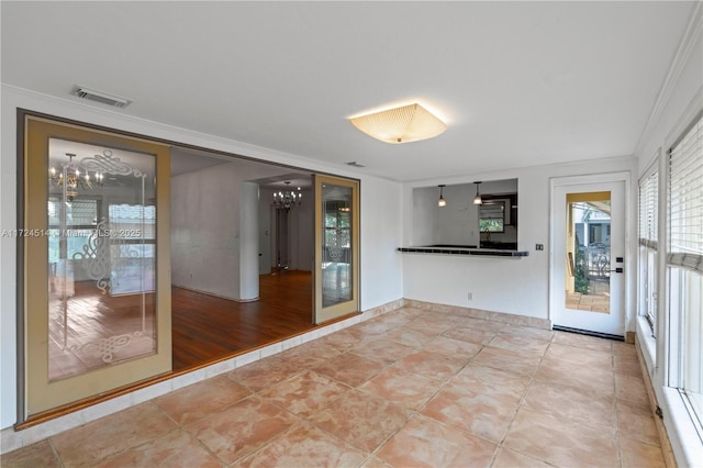 empty room featuring tile patterned flooring, ornamental molding, and an inviting chandelier