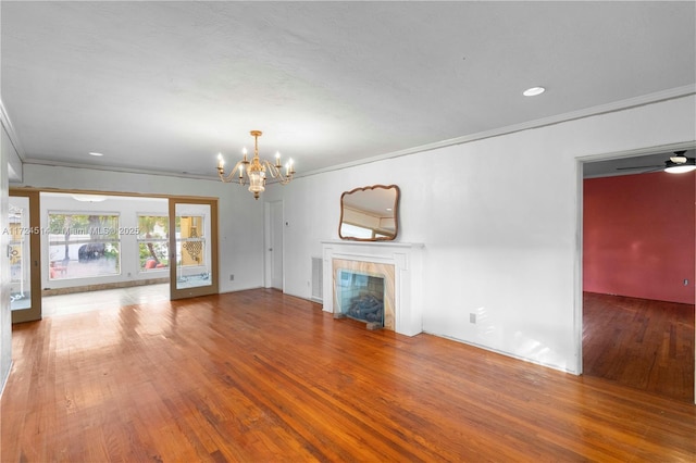 unfurnished living room featuring a tiled fireplace, crown molding, and hardwood / wood-style floors