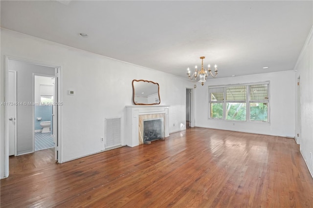 unfurnished living room featuring hardwood / wood-style flooring, ornamental molding, and a chandelier