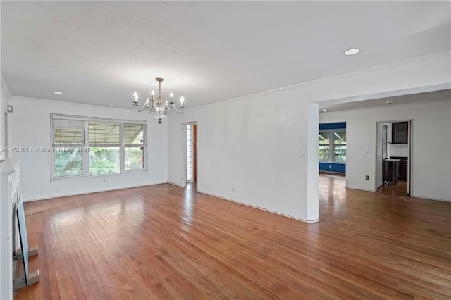 unfurnished living room with an inviting chandelier and wood-type flooring