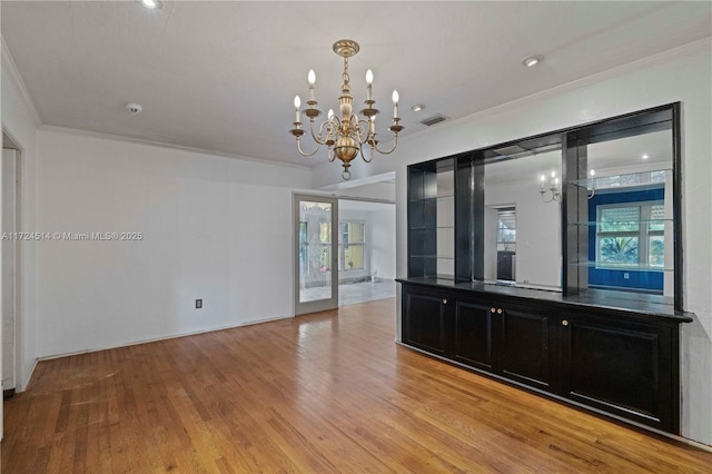 interior space with crown molding, plenty of natural light, a notable chandelier, and light hardwood / wood-style floors