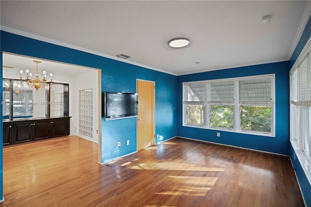 unfurnished living room featuring crown molding, an inviting chandelier, and light hardwood / wood-style floors