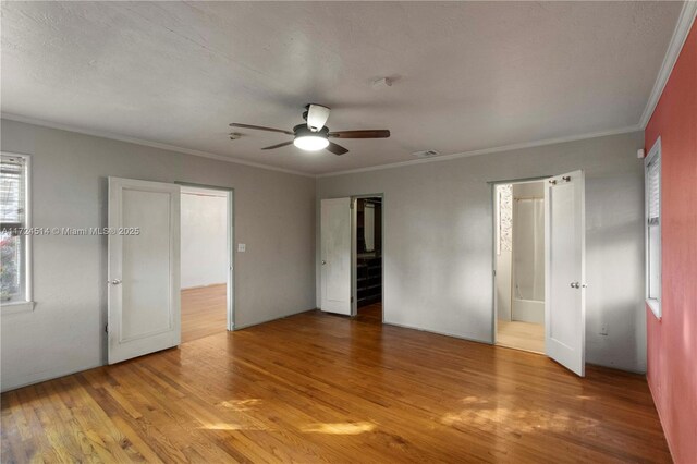 unfurnished bedroom featuring ornamental molding, light wood-type flooring, a textured ceiling, and ceiling fan