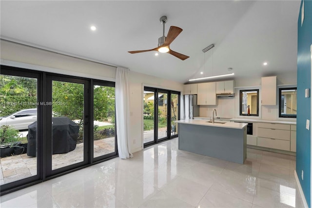 kitchen featuring lofted ceiling, sink, stainless steel fridge, ceiling fan, and a kitchen island with sink