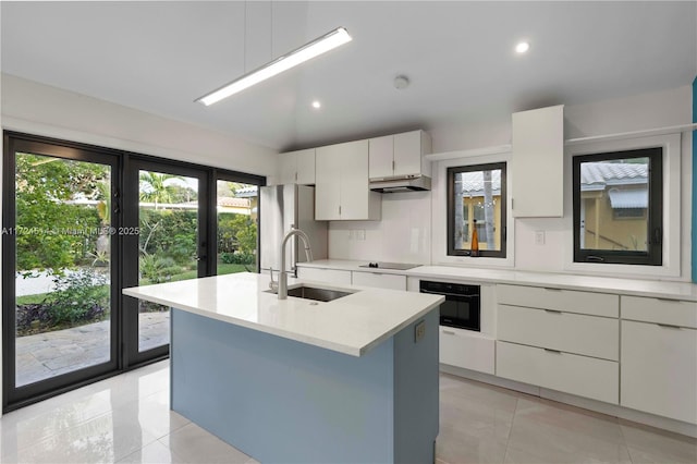 kitchen featuring an island with sink, sink, white cabinets, and black appliances