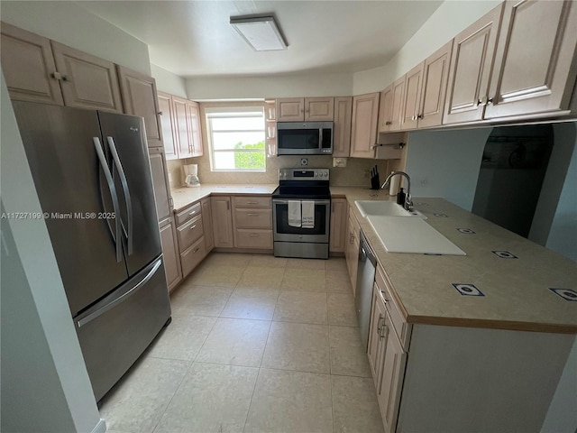 kitchen featuring light countertops, light brown cabinets, appliances with stainless steel finishes, and a sink