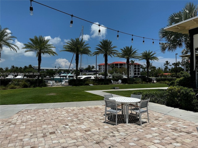 view of community featuring outdoor dining space, a lawn, and a patio