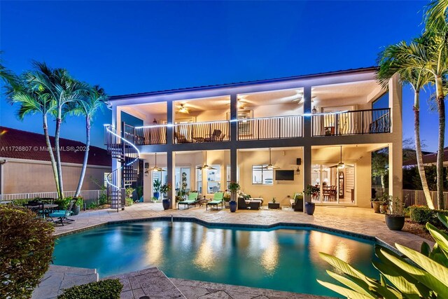 back of property with ceiling fan, a fenced in pool, a balcony, and a patio