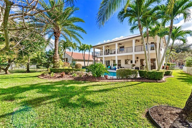 exterior space with ceiling fan, a balcony, and a fenced in pool