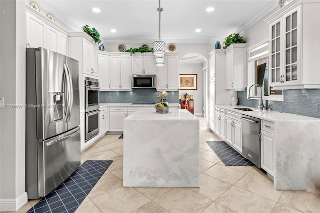 kitchen with stainless steel appliances, glass insert cabinets, white cabinets, a sink, and a kitchen island