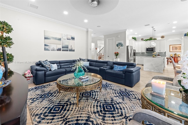 living room featuring light tile patterned floors, stairs, arched walkways, and ornamental molding