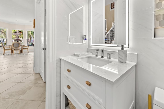 bathroom featuring tile walls, toilet, ornamental molding, vanity, and tile patterned flooring