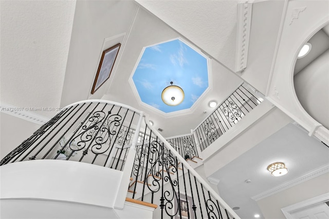 stairway featuring a high ceiling and ornamental molding