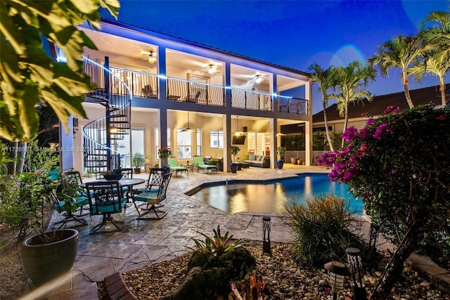 pool at twilight featuring an outdoor pool, ceiling fan, stairway, and a patio