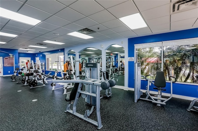 gym with visible vents, a paneled ceiling, and baseboards